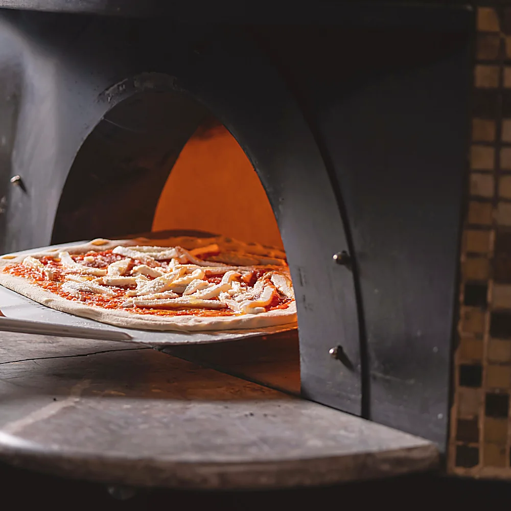 La bocca del forno con una pizza in cottura
